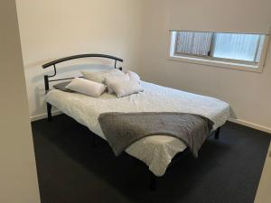 um quarto com uma cama com almofadas e uma janela em Comfy nest 4 bed room family house em Melton South