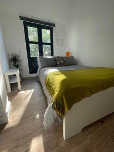 a bedroom with a bed with a yellow blanket on it at Bonjóia Porto Guest House in Porto