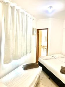 2 Betten in einem Zimmer mit weißen Vorhängen in der Unterkunft Flats Sierra Bela Vista in Goiânia