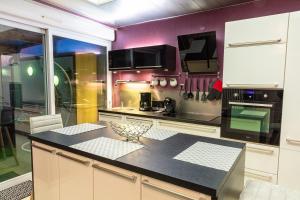 a kitchen with purple walls and a black counter top at Maison de Ville restylée avec jardin, proche gare in Dunkerque