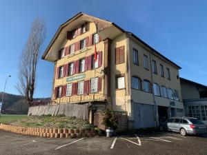 un edificio con un coche aparcado en un aparcamiento en Hotel Schönbrunnen, en Münchenbuchsee