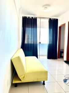 einen gelben Stuhl in einem Zimmer mit Fenster in der Unterkunft Flats Sierra Bela Vista in Goiânia