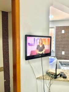 uma televisão na parede com uma mulher nela em Flats Sierra Bela Vista em Goiânia