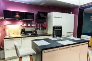 une cuisine avec des placards blancs et un mur violet dans l'établissement Maison de Ville restylée avec jardin, proche gare, à Dunkerque