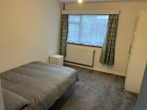 1 dormitorio con cama y ventana en 5 Bedroom House with outdoor space, en Upminster