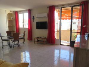 een woonkamer met rode gordijnen en een tafel en stoelen bij NICE NORD 2 PIECES CALMES,WIFI,CLIM,BALCON,PARKING in Nice
