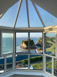 an arched window in a house with a view of the ocean at Blue Horizon Penthouse - amazing views + parking! in Newquay