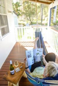 una mujer acostada en una hamaca leyendo un libro en Bush & Bay Cottage, en Erowal Bay