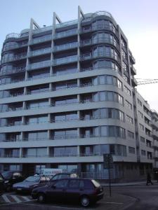 een groot gebouw met auto's ervoor geparkeerd bij Luxe appartement, zeezicht, garage en topligging in Oostende