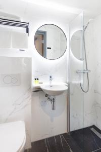 een witte badkamer met een wastafel en een spiegel bij Ciao Papa Hotel Amsterdam Central Station in Amsterdam