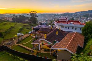 a house on a hill with a sunset in the background at The Hosteller Ooty in Ooty