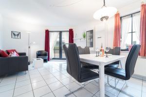 een eetkamer en een woonkamer met een witte tafel en stoelen bij Haus Titania Wohnung 1 in Grömitz