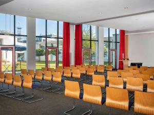 una sala de conferencias con sillas naranjas y cortinas rojas en Greet hotel Darmstadt - an Accor hotel - en Darmstadt