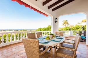 uma sala de jantar com uma mesa e cadeiras numa varanda em Villa Nineta em Son Bou