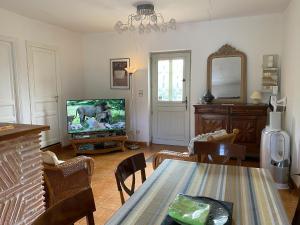 a living room with a tv and a dining room table at Le gîte de Pouzatel proche Château de Bonaguil in Fumel +4 photos
