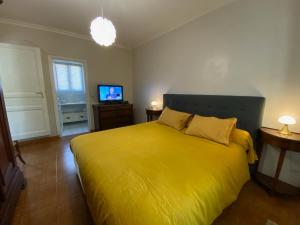 a bedroom with a yellow bed and a television at Le gîte de Pouzatel proche Château de Bonaguil in Fumel