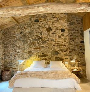 ein Schlafzimmer mit einer Steinmauer und einem Bett in der Unterkunft Lar do Gado in Porta