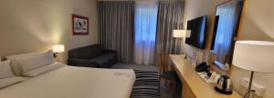 a hotel room with a large bed and a couch at Novotel Manchester West in Worsley
