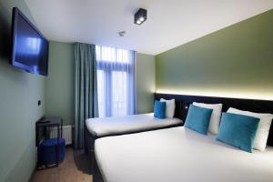 a hotel room with two beds and a flat screen tv at Ciao Papa Hotel Amsterdam Central Station in Amsterdam