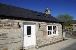 um edifício de pedra com uma porta branca e janelas em The Old Schoolhouse Lochearnhead em Lochearnhead