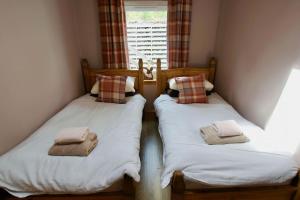 two twin beds in a room with a window at The Old Schoolhouse Lochearnhead in Lochearnhead