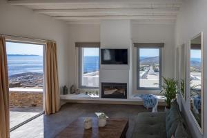 a living room with a fireplace and a view of the ocean at Kapsalos Villas in Agios Romanos