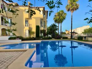a swimming pool in front of a building with palm trees at Beach Penthouse Apartment in Jávea