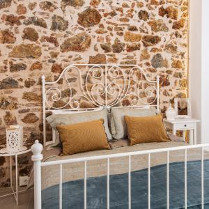 a white bed with two pillows in front of a stone wall at Athena Luxury Studios in Athens