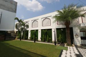 un edificio blanco con palmeras delante en Hotel Darbar-E-Khas A member of Crimson Hotels, en Bareilly
