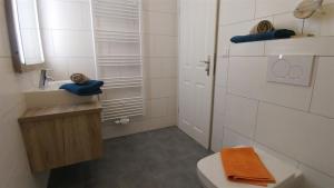 ein weißes Bad mit einem Waschbecken und einem WC in der Unterkunft Ferienwohnung Rapsspeicher - Landlust Osterwarf in Norddeich
