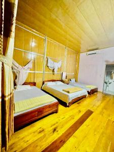Ba Be Lake View Homestay في An Ma: سريرين في غرفة ذات أرضيات خشبية