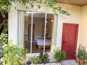 eine rote Tür eines Hauses mit einem Bett in der Spiegelung in der Unterkunft Rehendhi Villa in Maafushi