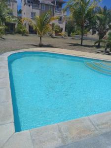 uma grande piscina azul em frente a uma casa em Relaxing 3 bedrooms Duplex with swimming pool em Grand Gaube