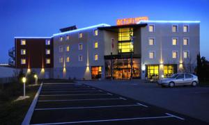 a building with a car parked in a parking lot at The Originals Boutique, Actuel Hôtel, Saint-Etienne Aéroport in Andrézieux-Bouthéon