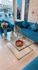 فندق تاج الإيمان في المدينة المنورة: غرفة معيشة مع أريكة زرقاء وطاولة زجاجية