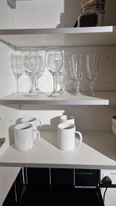 a shelf with wine glasses and cups on it at Spacious 1 Br Near Lincoln City Centre Amenities in Lincoln