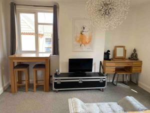 a living room with a tv and a table and a desk at Stylish & Modern Central Studio Apartment Free parking in Southampton