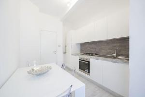 una cucina bianca con tavolo bianco e lavandino di La dolce vita - Pescara Centro a Pescara