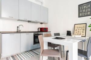 a kitchen with white cabinets and a white table and chairs at La casa sull'albero City Life in Milan