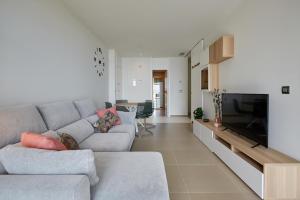 sala de estar con sofá gris y TV en Intempo Sky Apartments 096, en Benidorm