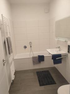 ein Badezimmer mit einem Waschbecken und einer Badewanne mit einem Waschbecken in der Unterkunft Ferienhaus mit privatem Seezugang, Sauna, Strand, Wassersport, Ruderboot, Stand Upp in Barßel + 13 Fotos