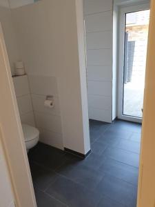 ein Badezimmer mit Toilette und Fenster in der Unterkunft Ferienhaus mit privatem Seezugang, Sauna, Strand, Wassersport, Ruderboot, Stand Upp in Barßel