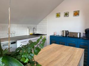 een keuken met blauwe kasten en een houten tafel bij Ferienwohnung Fuchs in Himmelkron