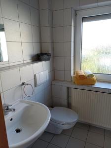 ein Bad mit einem Waschbecken, einem WC und einem Fenster in der Unterkunft Zimmer Frei 1 in Wiesbaden