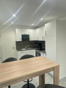 a kitchen with white cabinets and a wooden table at Ferienwohnung H&M Immobilien - Geiseltalsee in Braunsbedra