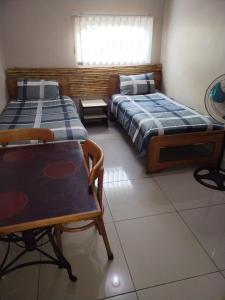 two beds in a room with a table and chairs at Lotus Guest House 1 in Durban