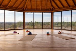 una stanza con una fila di tappetini per yoga davanti alle finestre di Quinta Marugo Retreats a Serpa