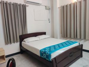 ein kleines Schlafzimmer mit einem Bett und Vorhängen in der Unterkunft Roshini Serviced Apartments in Chennai