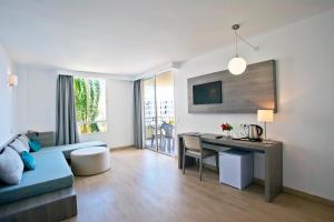 a living room with a blue couch and a desk at Aparthotel Playa Dorada in Sa Coma