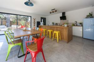 a kitchen with a wooden table and colorful chairs at Contemporary house with heated pool in a magnificent pine forest in Aigues-Mortes